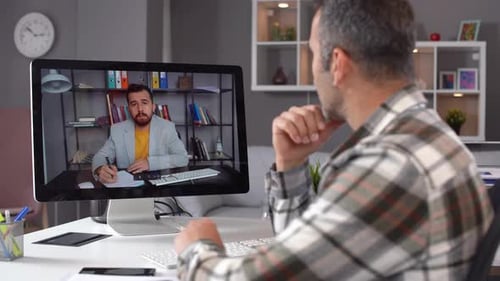 Man Teleconferencing from Home Office Taking Notes