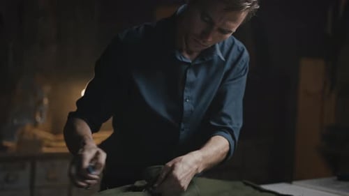 Man Carefully Removing Stitches from Green Canvas