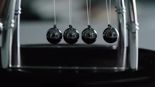 Swinging Newton's Cradle Demonstrating Kinetic Energy and Momentum