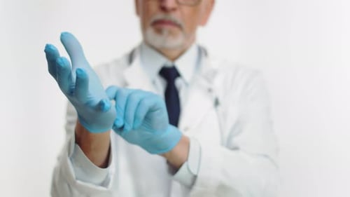 Doctor Puts on Blue Surgical Gloves in Clinic