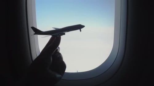 Holding Toy Airplane Against Airplane Window