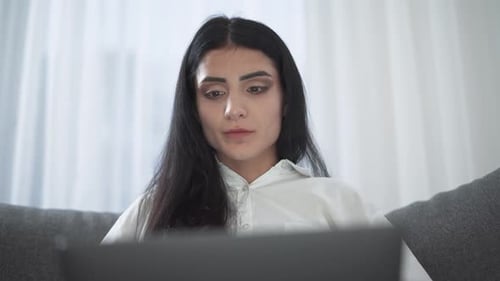 Woman Using Laptop Computer on Sofa at Home