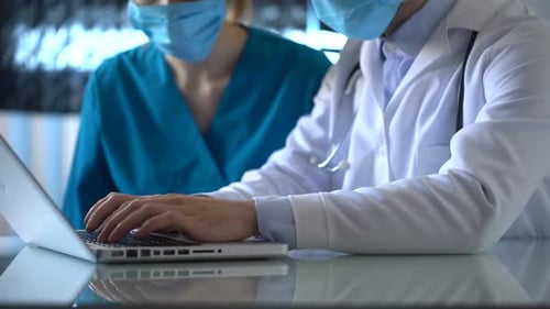 Doctors Typing on Laptop in Hospital