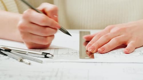Woman's Hands Drawing Architectural Blueprint with Ruler