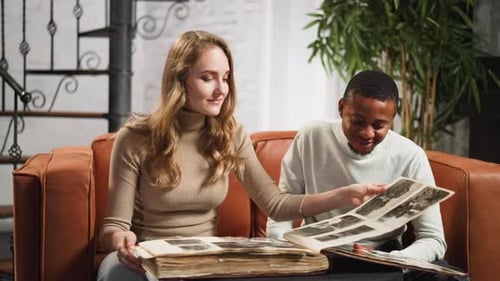Mujer muestra un viejo álbum de fotos familiares a un hombre en la sala de estar