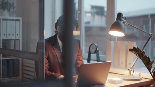 Young Male Entrepreneur Working on Laptop at Office Desk in the Evening
