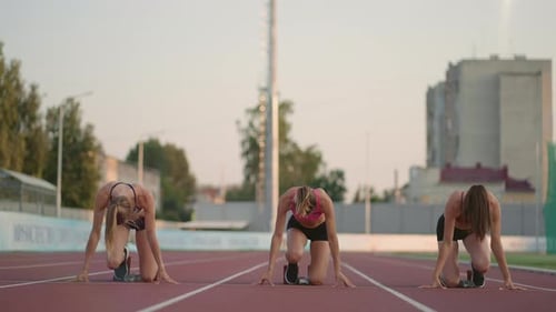Athletic Women at Track Starting Line Prepare to Race