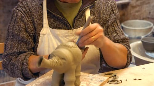 Craftsman Shapes Clay Elephant Sculpture in Workshop