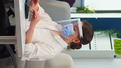 Woman Working at Computer Wearing Face Shield