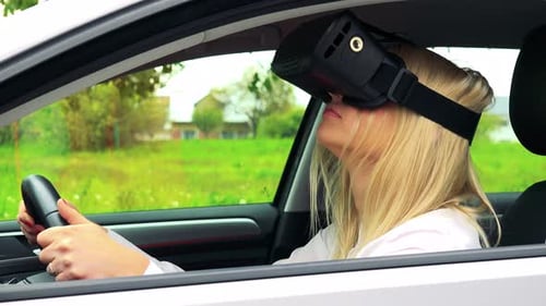 Young Attractive Blond Woman Sits in the Car and Uses Virtual Reality Glasses