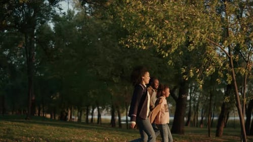 Family Walking Autumn Park Holding Hands Together in Evening Golden Sunlight