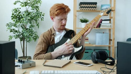 Young Adult Playing Electric Guitar at Home