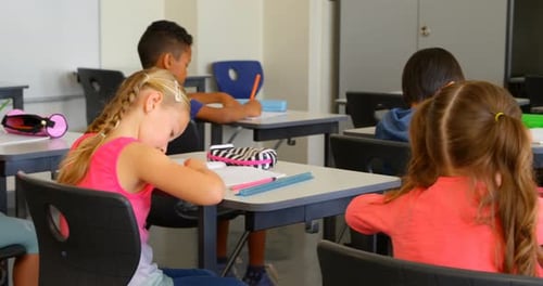 Multi-ethnic schoolkids studying at desk in a classroom at school 4k