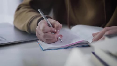 Hands of Millennial Caucasian Boy Writing in Workbook. Close-up of Male Palm with Pen. Diligent