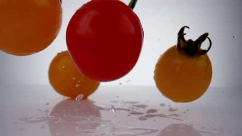 Camera follows cherry tomatoes falling on surface. Slow Motion.