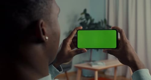 Man Holding Mobile in Horizontal Position with Green Screen