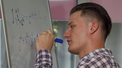 Young Adult Writing Math Equations on Whiteboard