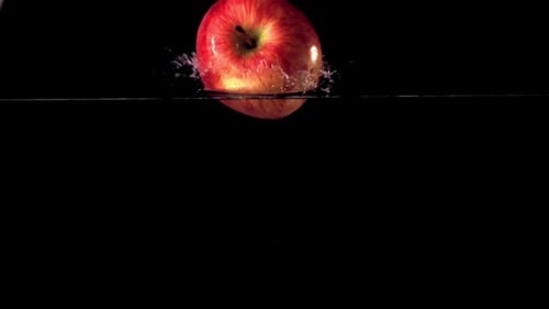 Super Slow Motion One Red Apple Falls Under the Water with Air Bubbles
