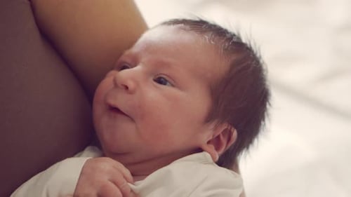 Newborn baby boy and his mother at home. Close-up portrait of the infant