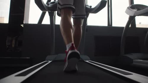 Male Athlete is Engaged in Cardio Training on Treadmill at Gym Back View
