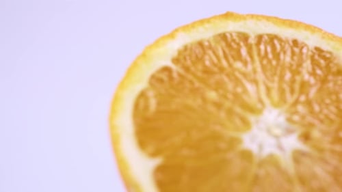 Feche a laranja valencia fresca cortada com fundo branco, foco raso e girando lentamente.