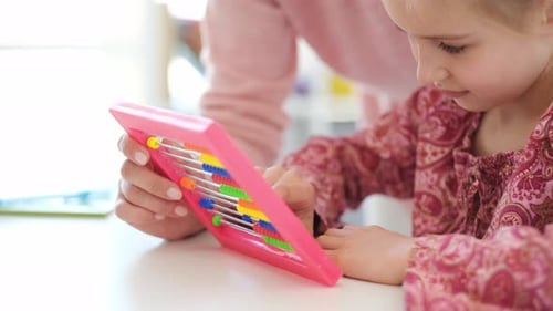 Girl Learning Math with Abacus at Table