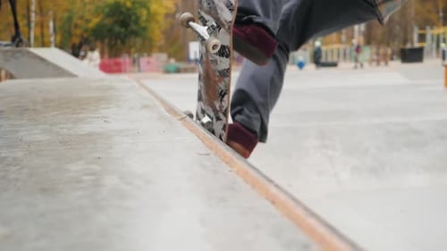 Skater Practicing in the Autumn Concrete Skate Park Making Tricks and Rides in Ramp