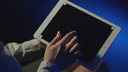 Woman Using Tablet in Dark Room at Night