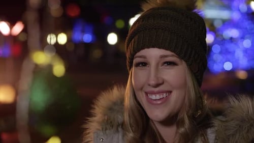 Happy Young Woman Smiling at Christmas Lights