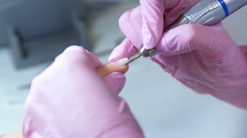 Beautician Hands in Gloves Removing Cuticles with Polish Machine