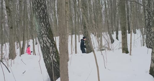 A Man and a Woman Run in the Park in Winter and Jump Over a Fallen Tree. Step Over the Obstacle
