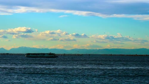 Boat Sails on Blue Sea with Ripple Against Coastline
