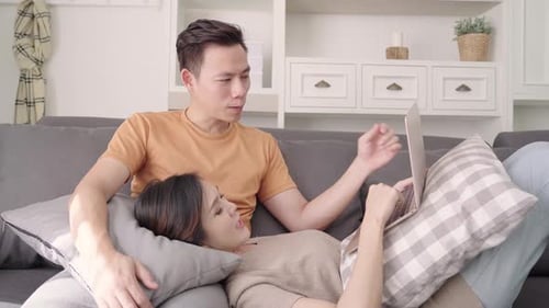 Relaxed Couple Using Laptop on Sofa at Home