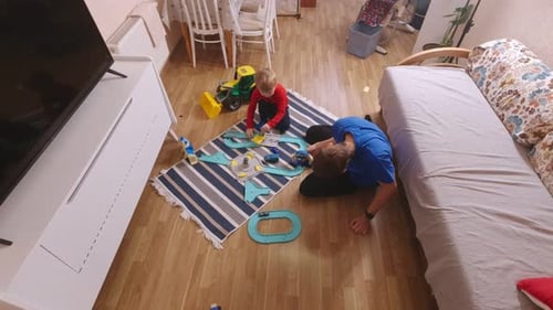 Father and Child Playing with Toy Car Racetrack