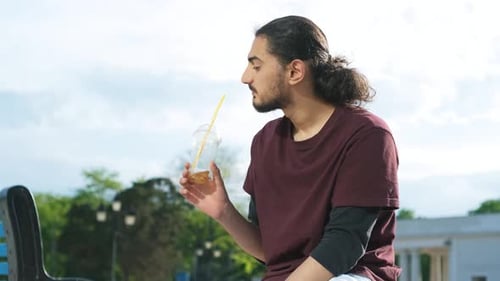 Closeup Portrait of Handsome Arab Man Sitting in the Park and Drinking Coffee Tonic