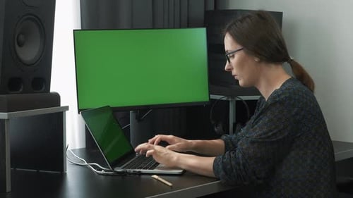 Weibliche Angestellte, die von zu Hause aus am Greenscreen am Laptop arbeitet.