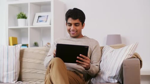 Smiling Young Adult Using Tablet on Couch