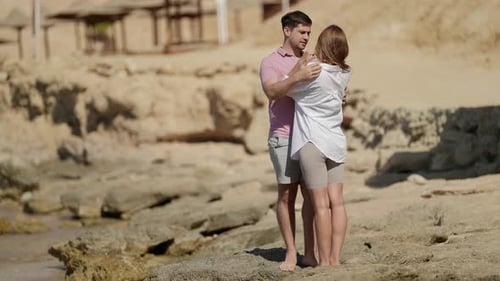 Charming Woman is Kissing Her Beloved Husband on Beach in Summer Day