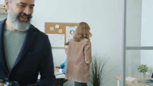 Friendly Office Worker Bringing Coffee to Colleague Then Working with Laptop Together
