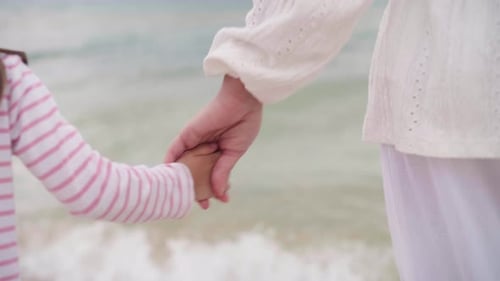 Mother With Little Daughter Walking Along the Sea Happy Family on the Beach Mother Holds Hand Little