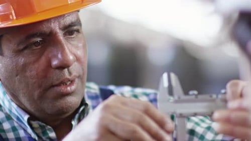 Industrial Worker Taking Measurement with Caliper