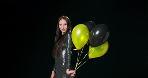Young Woman with Balloons Poses in Silver Dress
