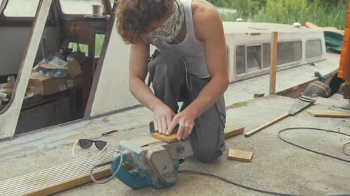 Sanding wooden block using belt sander boat maintenance outdoors, MID SHOT