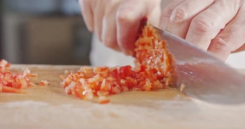 Slow motion close up of a chef knife slicing a Red bell pepper