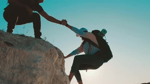 Man Helps Woman Climb Rocky Cliffside