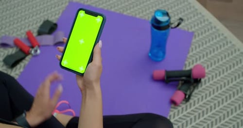 Fitness Woman Use Smartphone with Green Screen After Training at Home. Healthy Lifestyle. Stretching