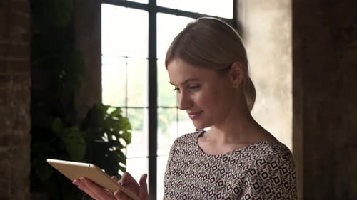 Young Woman Working In A Creative Office. Blond mature businesswoman with tablet in office.