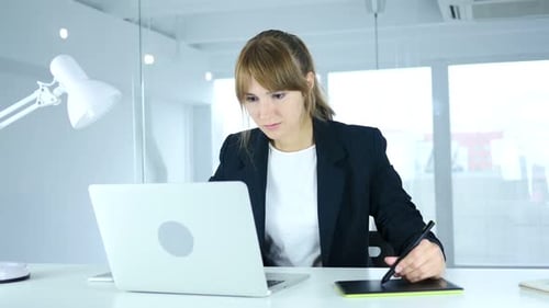 Woman Working on Laptop with Graphics Tablet at Desk