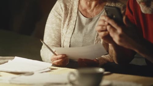 Pareja mayor calculando pagos de servicios públicos y bromeando
