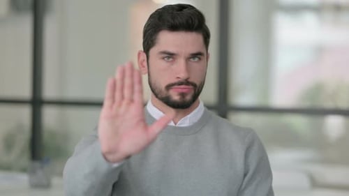 Young Adult Man Puts Hand Up To Stop
